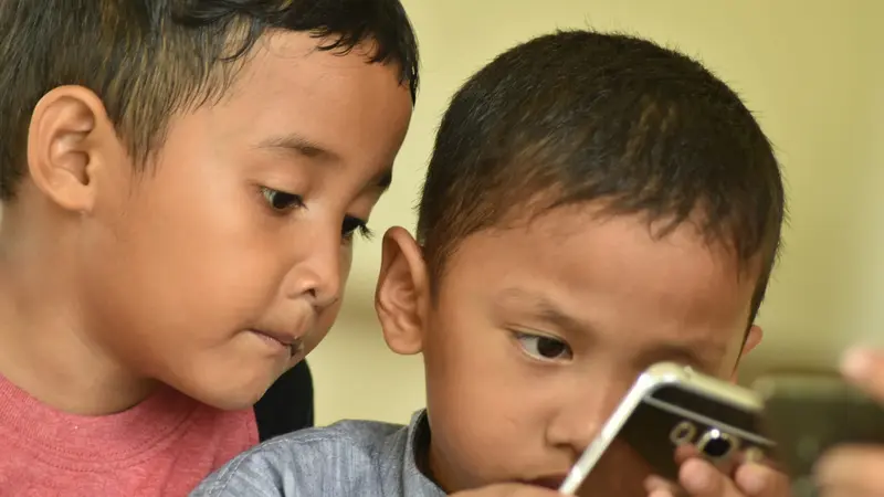 Two young boys looking closely at a phone